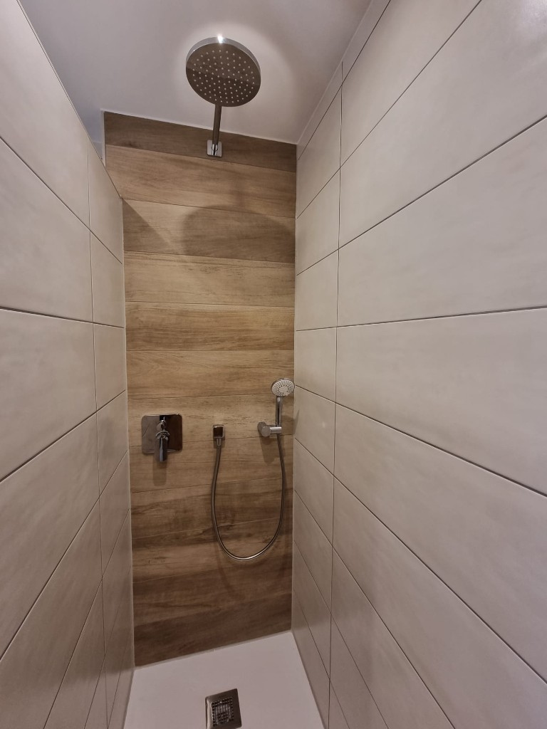 Dusche mit Fliesen in Holzoptik und Regenbrause